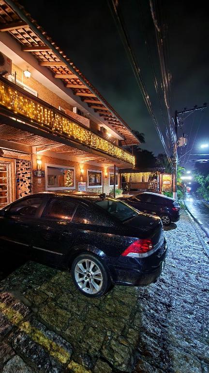 two cars parked in front of a building at night at Pousada Lacosta in Ilhabela