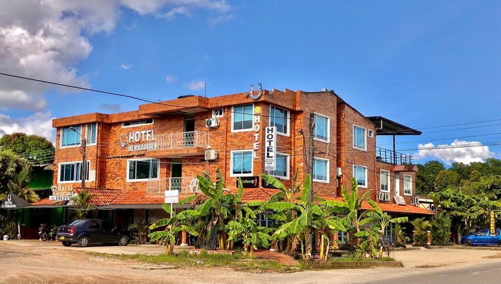a red brick building with trees in front of it at Hotel La Herradura in Puerto López