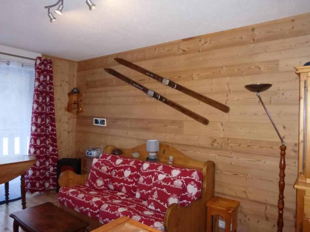 - un salon avec un canapé rouge et des murs en bois dans l'établissement Studio avec balcon à Barcelonnette, 4 couchages - FR-1-804-33, à Barcelonnette