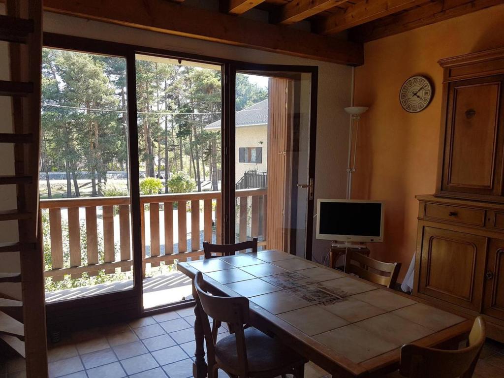 une salle à manger avec une table et une grande fenêtre dans l'établissement Duplex 3 pièces avec balcon, proche Barcelonnette - FR-1-804-35, à Saint-Pons