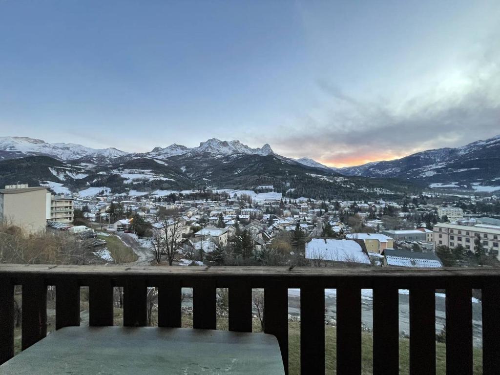un banc installé sur un balcon avec des montagnes enneigées dans l'établissement Charmant T2 à Barcelonnette avec balcon et parking - FR-1-804-43, à Barcelonnette