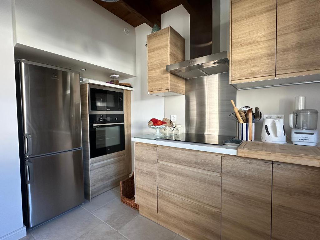 une cuisine avec des armoires en bois et un réfrigérateur en acier inoxydable dans l'établissement Villa rénovée avec WIFI, 3 chambres, terrasse, parking - La Palmyre - FR-1-705-90, aux Mathes