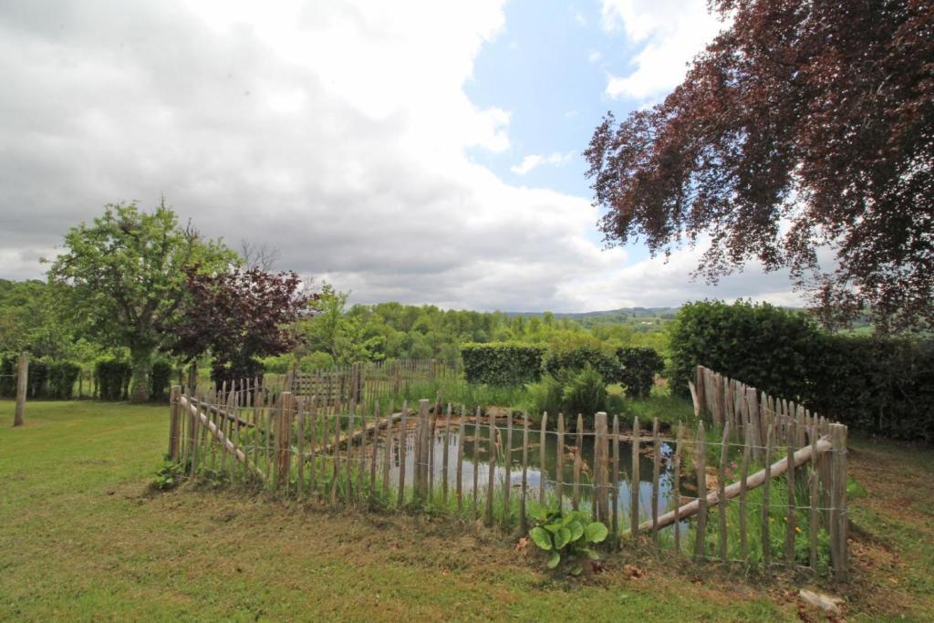 une clôture en bois dans une cour avec un étang dans l'établissement Les marronniers, à Sainte-Anne-Saint-Priest