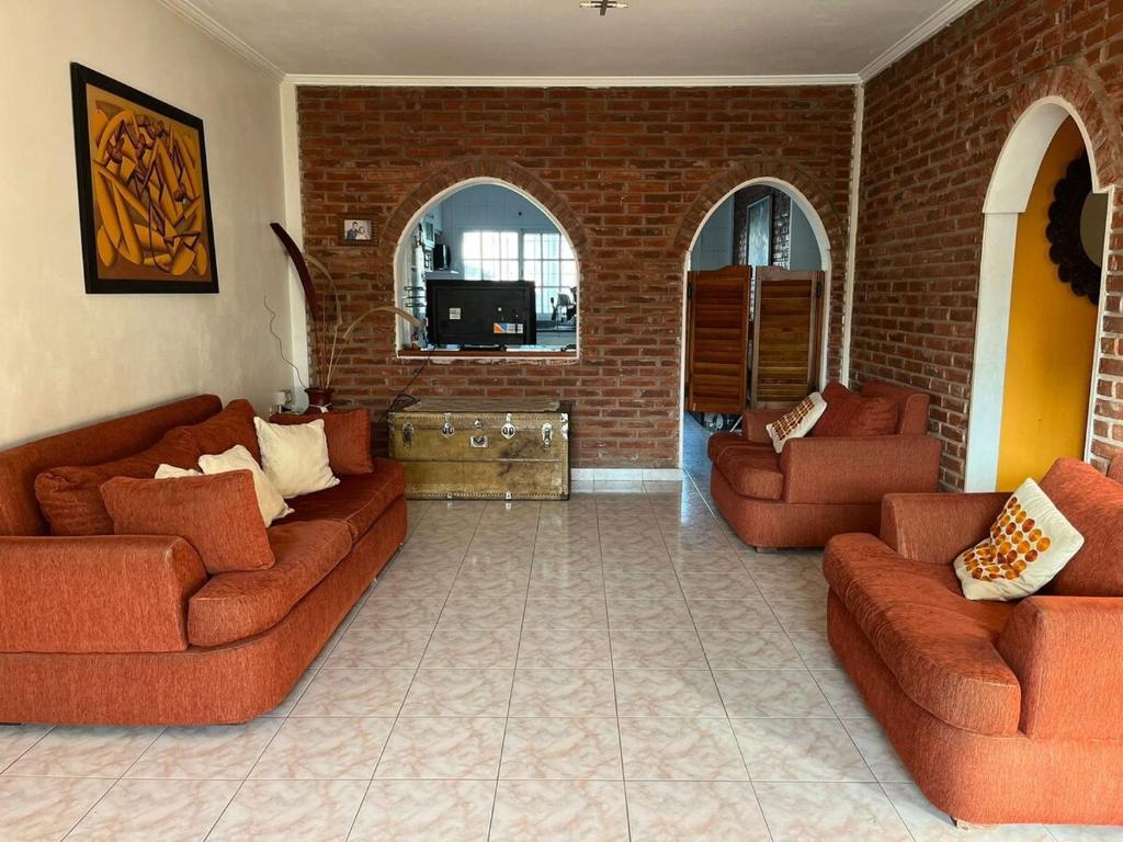 a living room with two couches and a brick wall at Spacious 3BDR house in Chivilcoy with swimming pool and view in Chivilcoy
