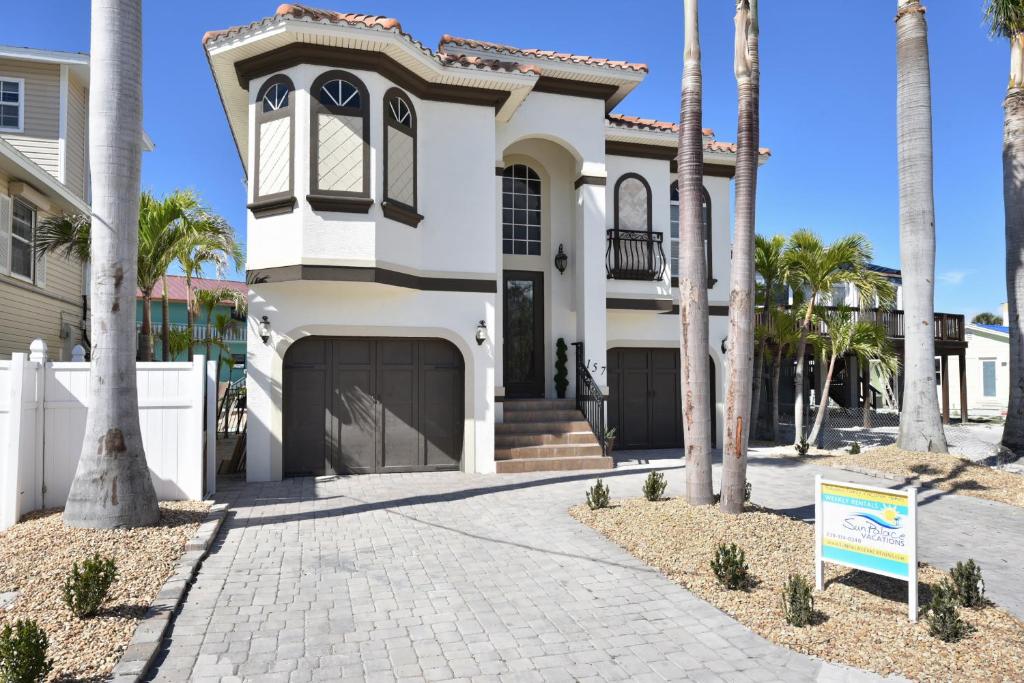 a white house with palm trees in front of it at Casa del Sol Breeze by Sun Palace Vacations in Fort Myers Beach