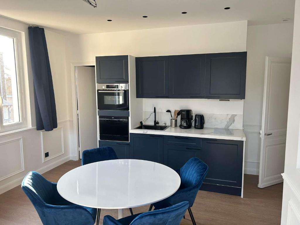 une cuisine avec une table blanche et des chaises bleues dans l'établissement Splendid appartement, à Rouen