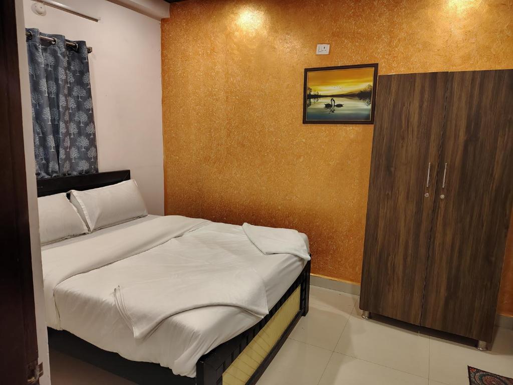 a small bedroom with a bed and a wooden cabinet at KOTLAS Highliving Service Apartments in Gachibowli