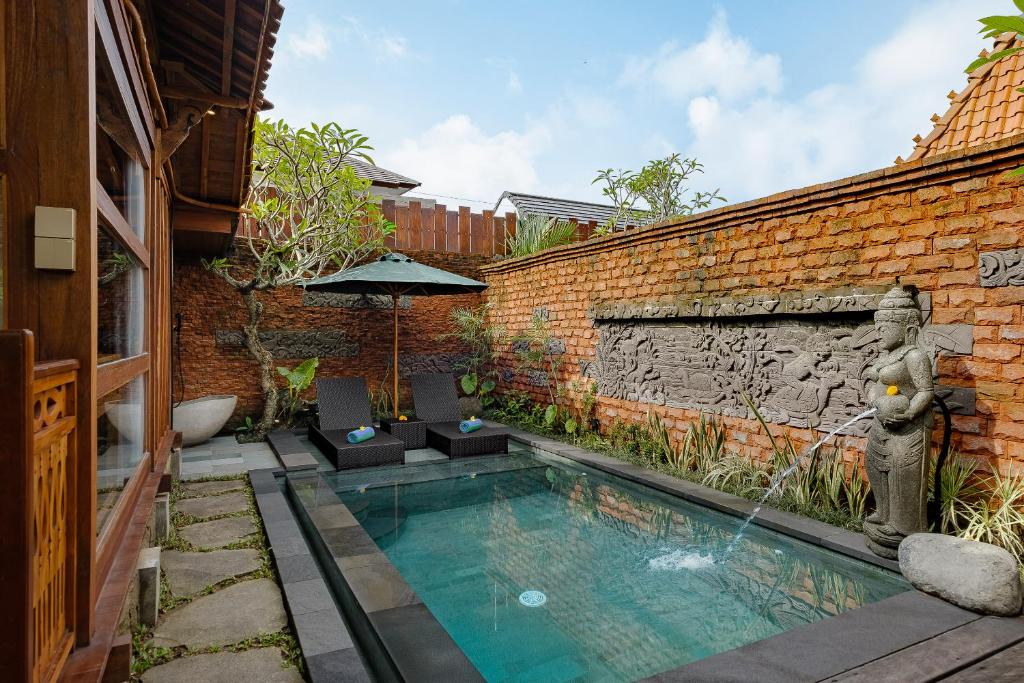 een zwembad voor een bakstenen gebouw bij Kappat Ubud Villa in Ubud
