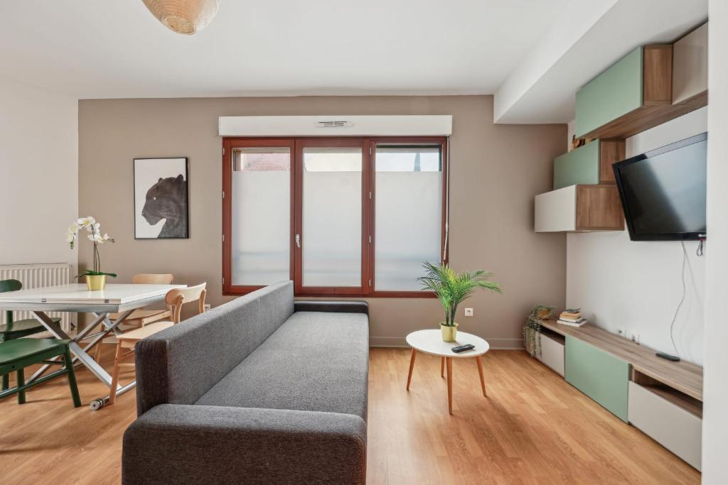a living room with a couch and a table at Grand Appart Rénové Paris et Disneyland 4pers in Neuilly-sur-Marne