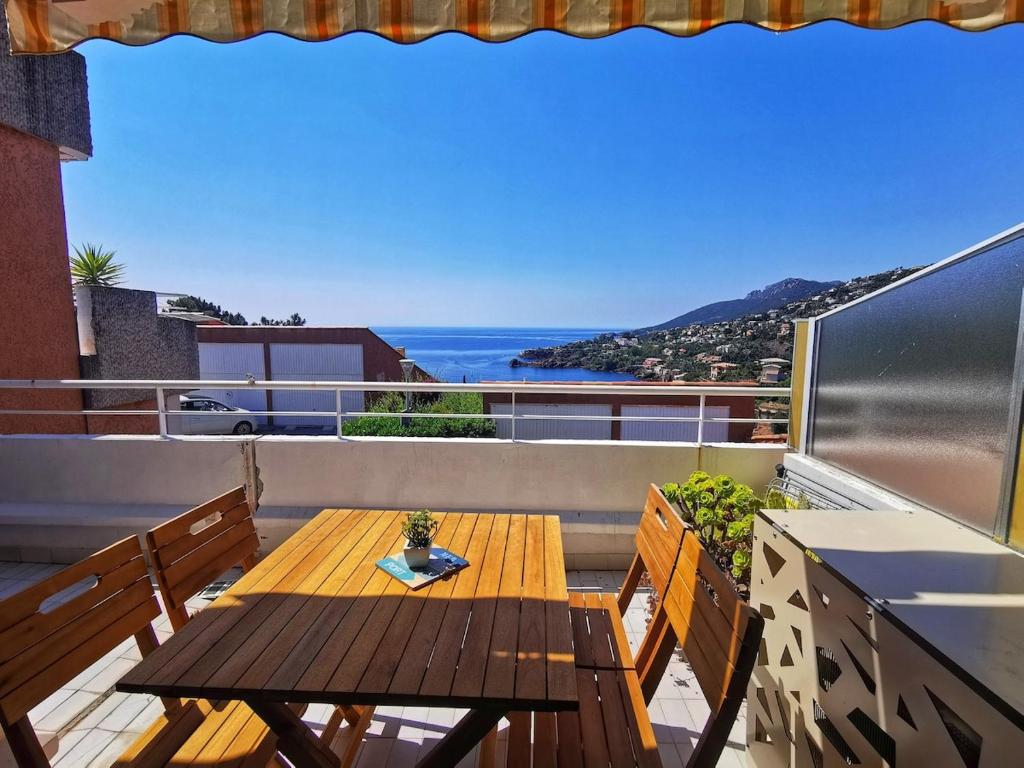 une table en bois sur un balcon avec vue sur l'océan dans l'établissement 4 pièces vue mer - Mas de la mer, à Théoule-sur-Mer