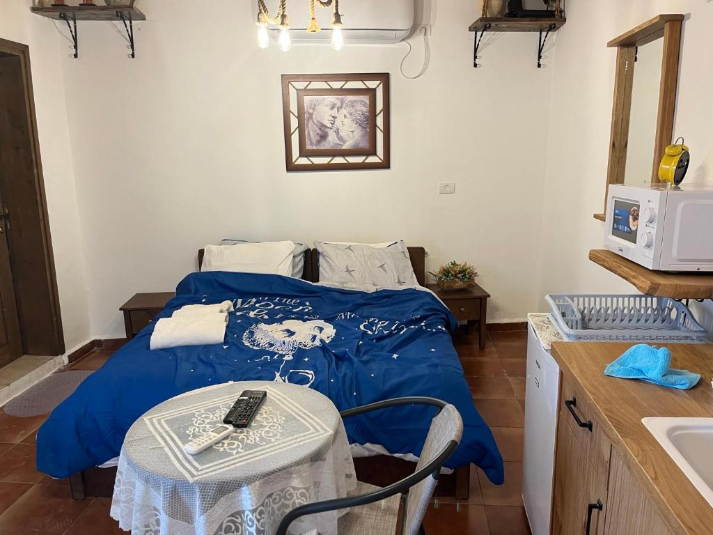 a bedroom with a bed with a blue blanket and a table at לומינוס האגוז in Ḥurfeish