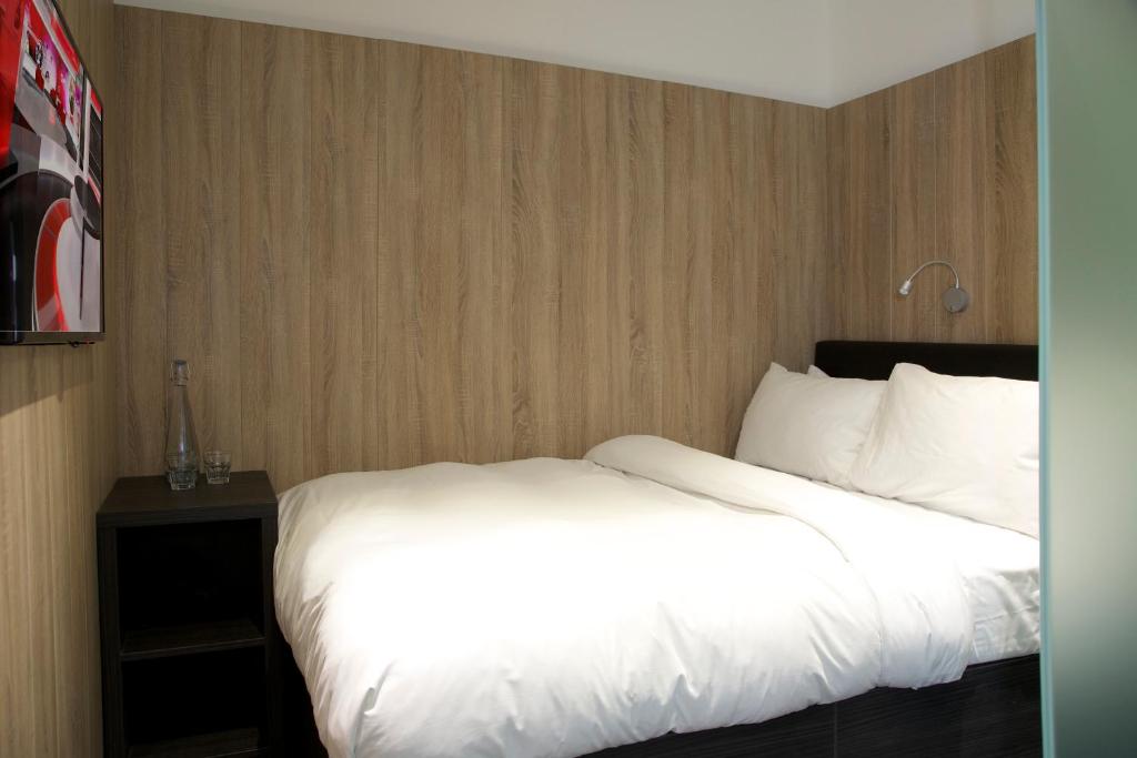 a bed with white sheets and pillows in a hotel room at The Z Hotel Victoria in London