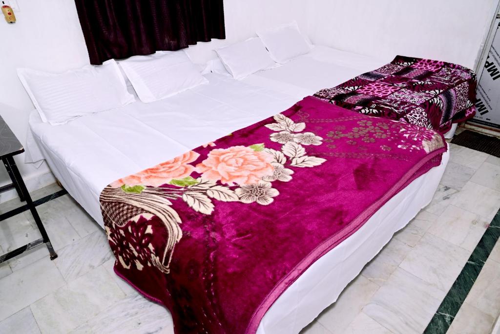 a white bed with a purple blanket with flowers on it at Shivay Guest house in Jasidih