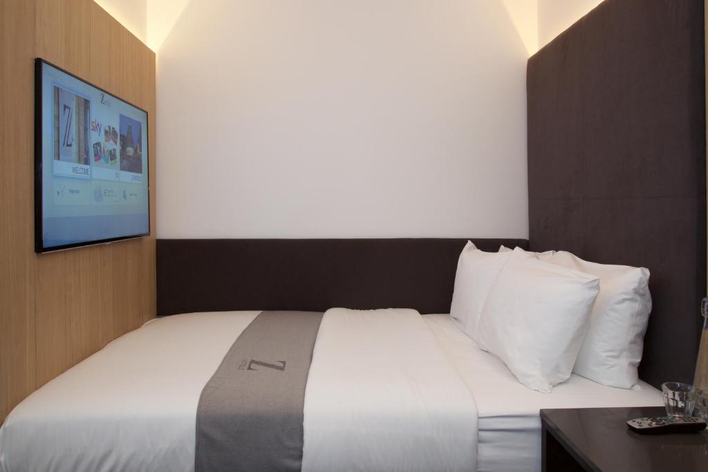 a bedroom with a large bed with a tv on the wall at The Z Hotel Victoria in London
