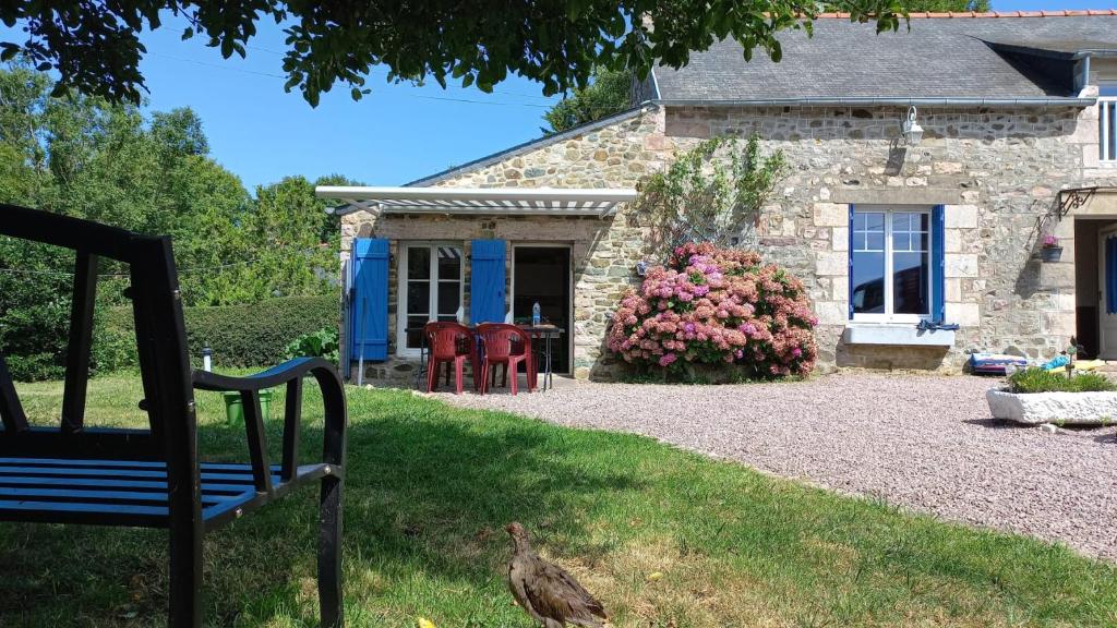 une maison en pierre avec un banc devant elle dans l'établissement Maison en pierre, à Saint-Pabu