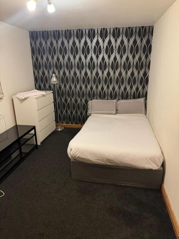 a small bedroom with a bed and a patterned wall at Peace House in Leeds