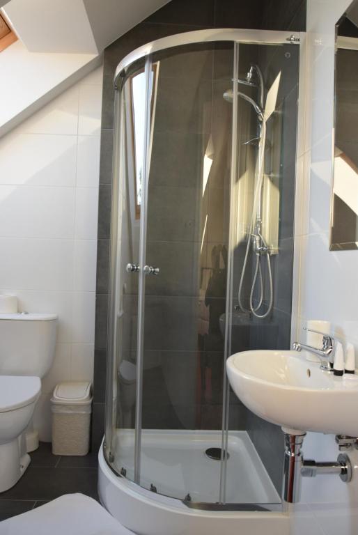 Compact attic bathroom with curved glass shower enclosure, white sink and toilet, bright natural light.