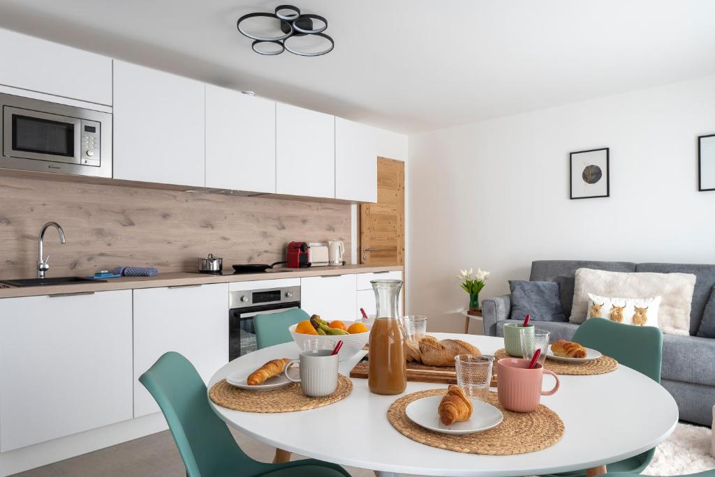 - une cuisine blanche avec une table et de la nourriture dans l'établissement Appartement Cabane des Neiges, aux Gets
