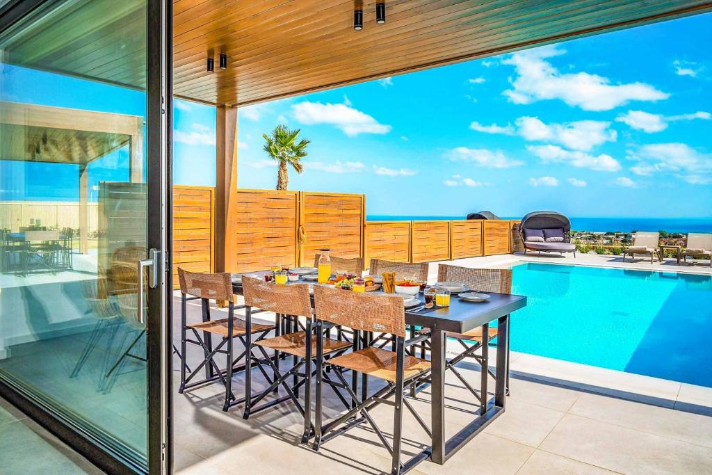 a dining room with a table and a swimming pool at Kamelia Villa 1 in Hersonissos