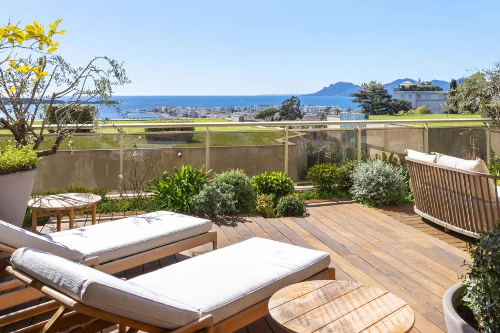 un patio avec des chaises et des tables sur une terrasse en bois dans l'établissement REF 1977 - Cannes Californie Sea View, à Cannes