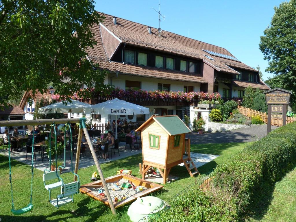 ein Spielhof mit einem Haus und einer Schaukel in der Unterkunft Café-Pension Endehof in Oberprechtal