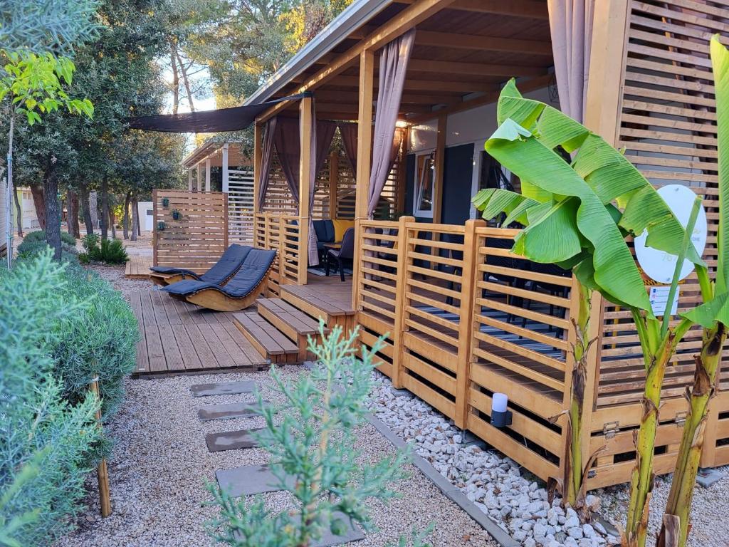 a house with a wooden porch with a chair on a deck at Ventura mobile home in Biograd na Moru