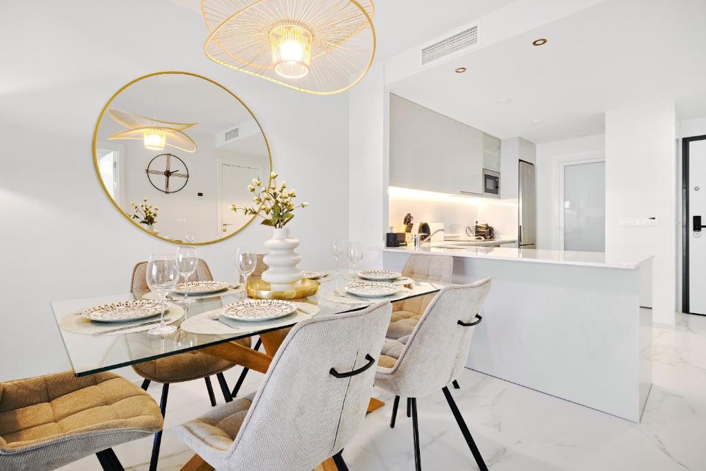 une salle à manger avec une table, des chaises et un miroir dans l'établissement Azure Carmel Apartment Flamenca Village, à Orihuela Costa