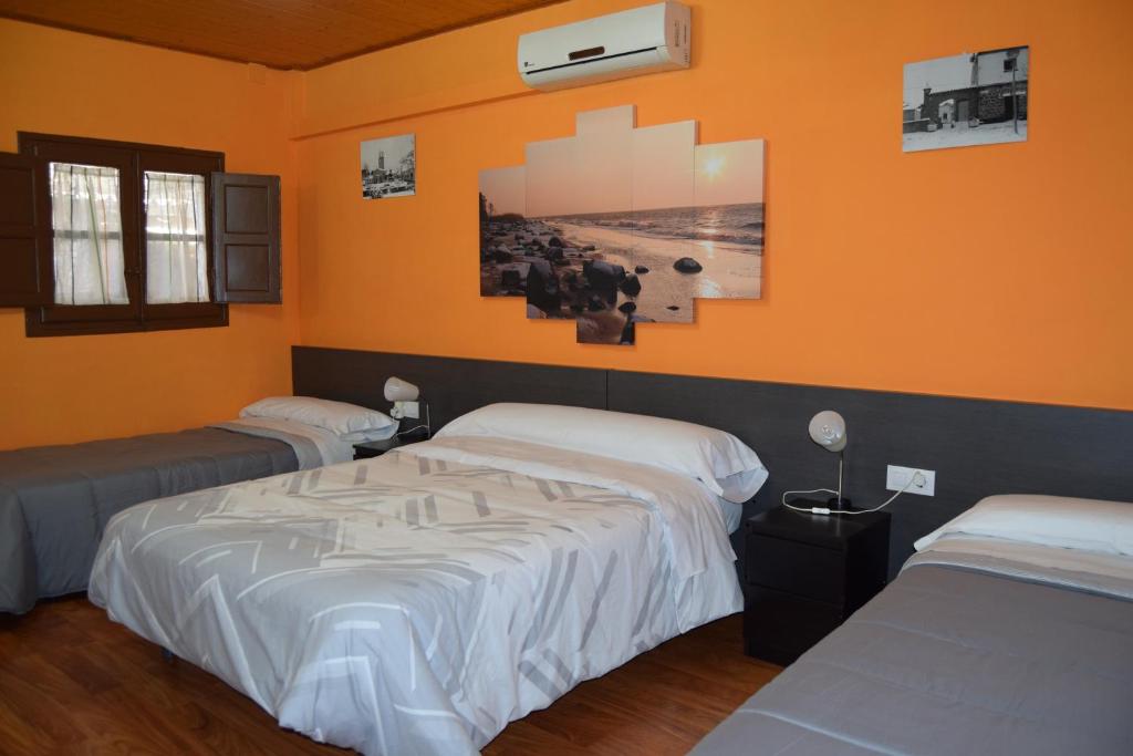 two beds in a room with orange walls at Habitación independiente en Casa Rural Javier in Valmuel