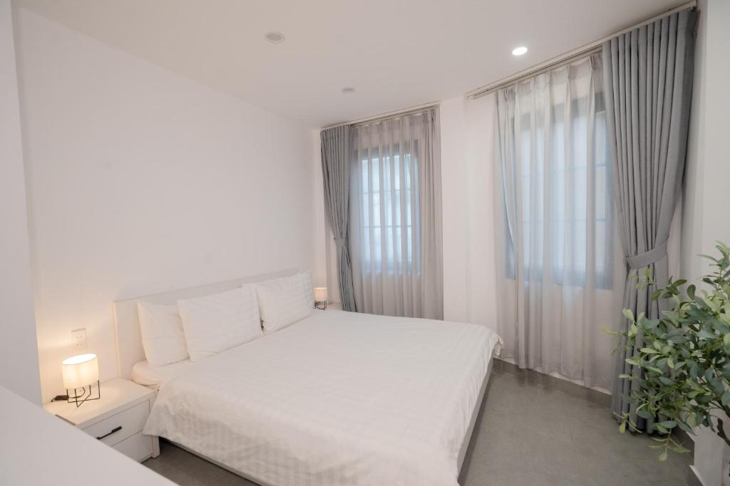 a bedroom with a white bed and two windows at PHAM Homes in Hai Phong