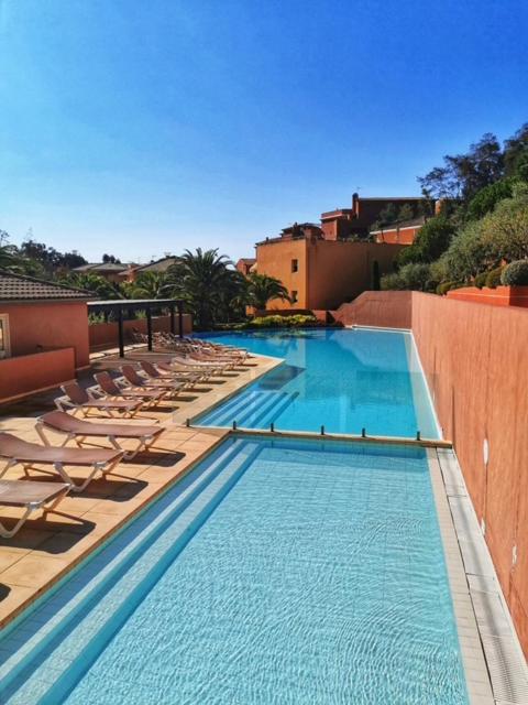 une grande piscine avec des chaises longues et un hôtel dans l'établissement Joli 2 pièces en bord de mer, à Théoule-sur-Mer