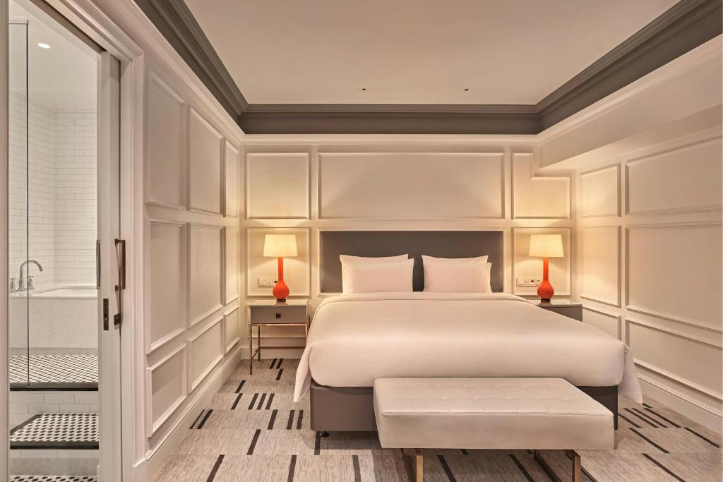 a bedroom with a large white bed and a tub at London Marriott Hotel County Hall in London