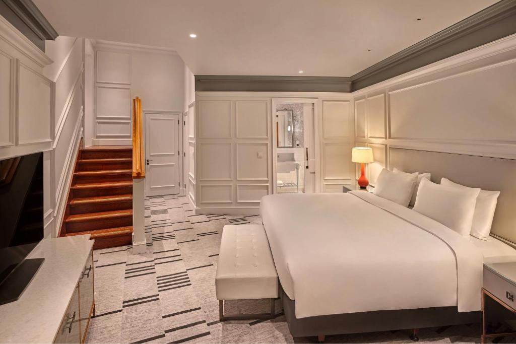 a bedroom with a large white bed and a staircase at London Marriott Hotel County Hall in London