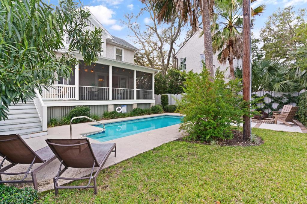 a house with a swimming pool and two chairs in the yard at Delahunt Cottage - 4218 Seventh Street in Saint Simons Island