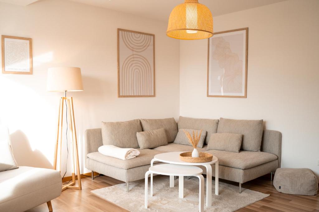 a living room with a couch and a table at C4S COME4STAY Altötting - 3-Zi Whg I Zentrale Lage I Parkplatz I Balkon I WIFI I SmartTV I 1 Kingsize, 1 Queensize Bett I Office Arbeitsplatz I Wohnbereich mit Couch und Essbereich I voll ausgestattete Küche I Nespresso in Altötting