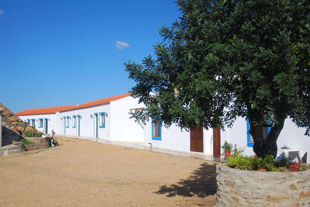 a white building with a tree in front of it at Paisagem do Guadiana Turismo Rural in Odeleite