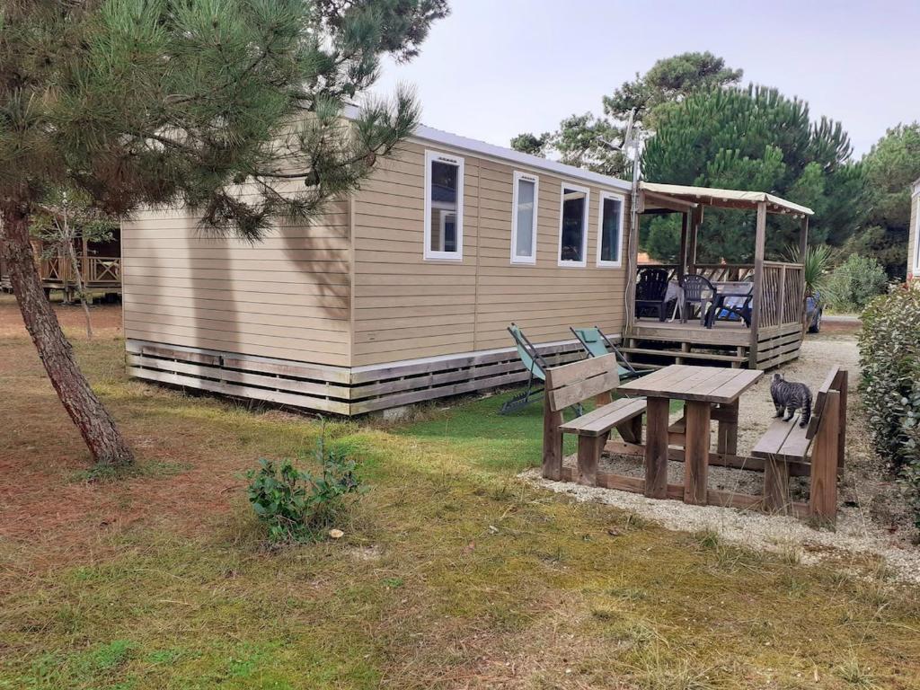 Une petite maison avec une table de pique-nique et un banc dans l'établissement Mobil-home dans camping 5 etoiles en bord de plage, à Montalivet-les-Bains