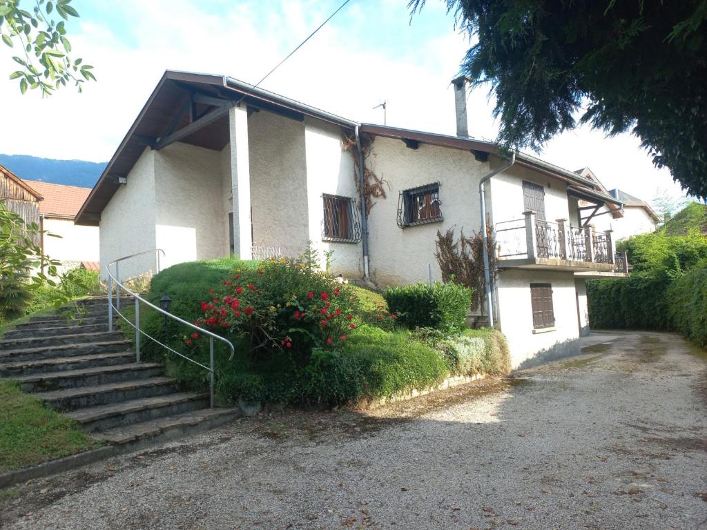 une maison blanche avec des escaliers et des fleurs devant elle dans l'établissement l'appartement village, à Saint-Martin-d'Uriage
