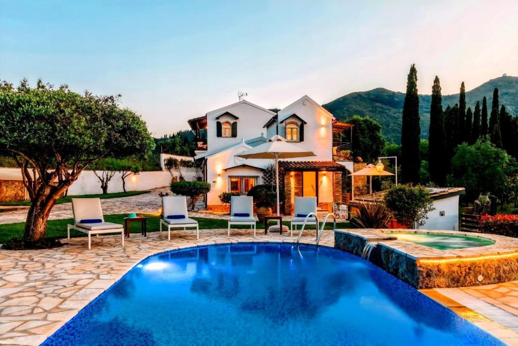 una villa con piscina di fronte a una casa di Villa Claire Corfu a Gastouri