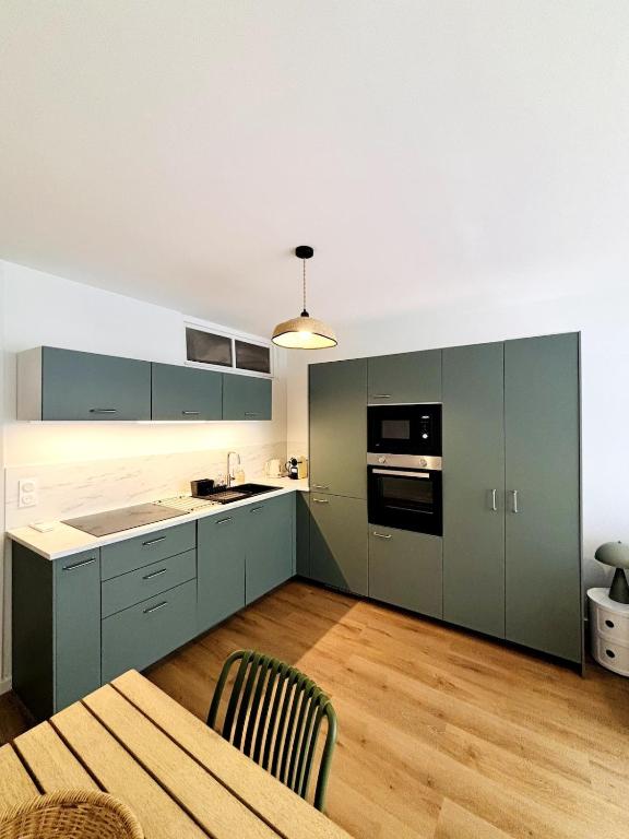 een keuken met groene kasten en een houten tafel bij Appartement Chic 50m de la mer in Palavas-les-Flots