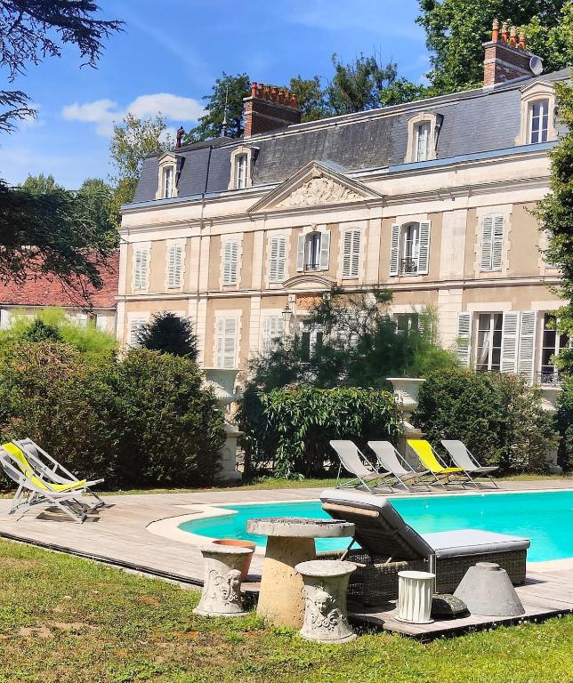 un grand bâtiment avec une piscine et des chaises longues dans l'établissement Château du Saulce, à Escolives-Sainte-Camille