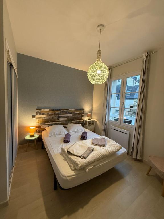 sypialnia z dużym łóżkiem i żyrandolem w obiekcie Appartement T2 vue sur la rivière avec garage privatif - Port de Saint-Goustan w mieście Auray