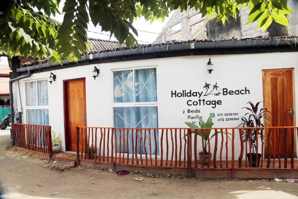 a beach cottage with a sign on the side of it at Holiday Beach Cottage in Ahangama