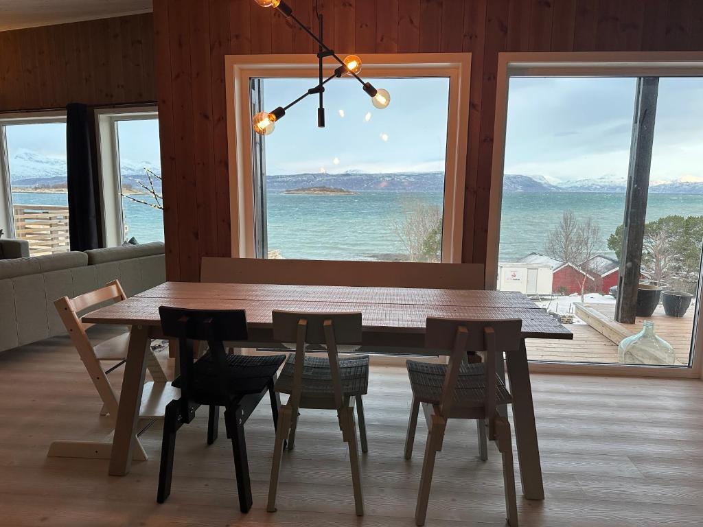 a dining room table and chairs with a view of the ocean at Northern Lights Lodge in Narvik