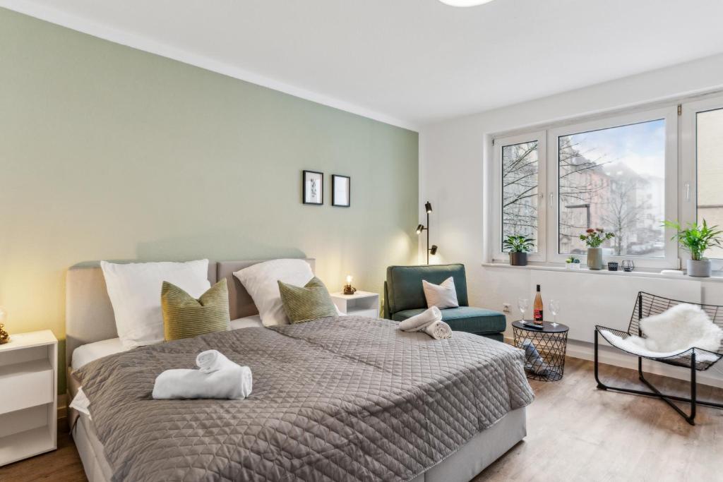 a bedroom with a large bed and two chairs at SHINY HOMES - Trendy Apartment Close to City Center in Bielefeld