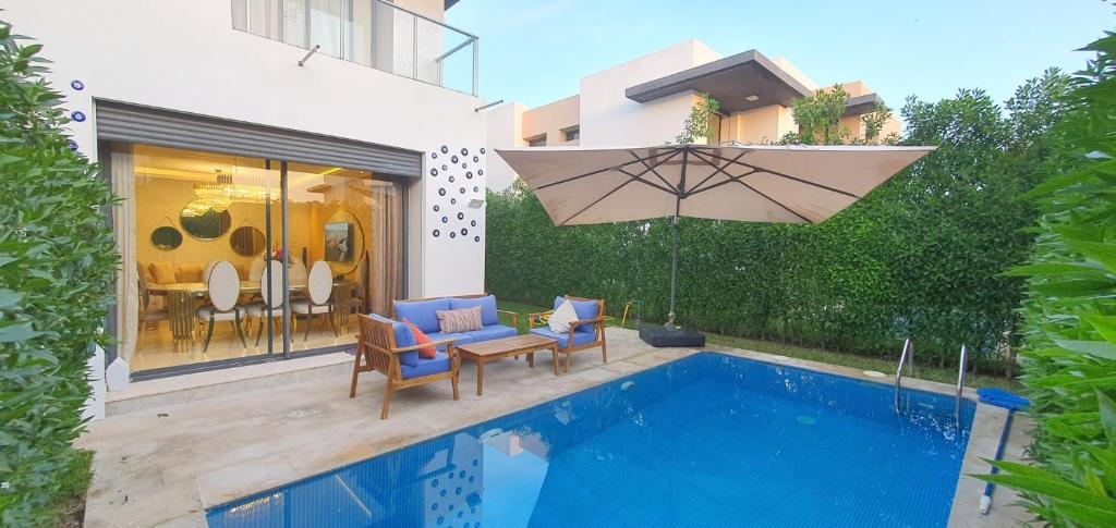 カサブランカにあるLuxury Villa with Private Poolの家の隣に椅子とパラソル付きのプールがあります。