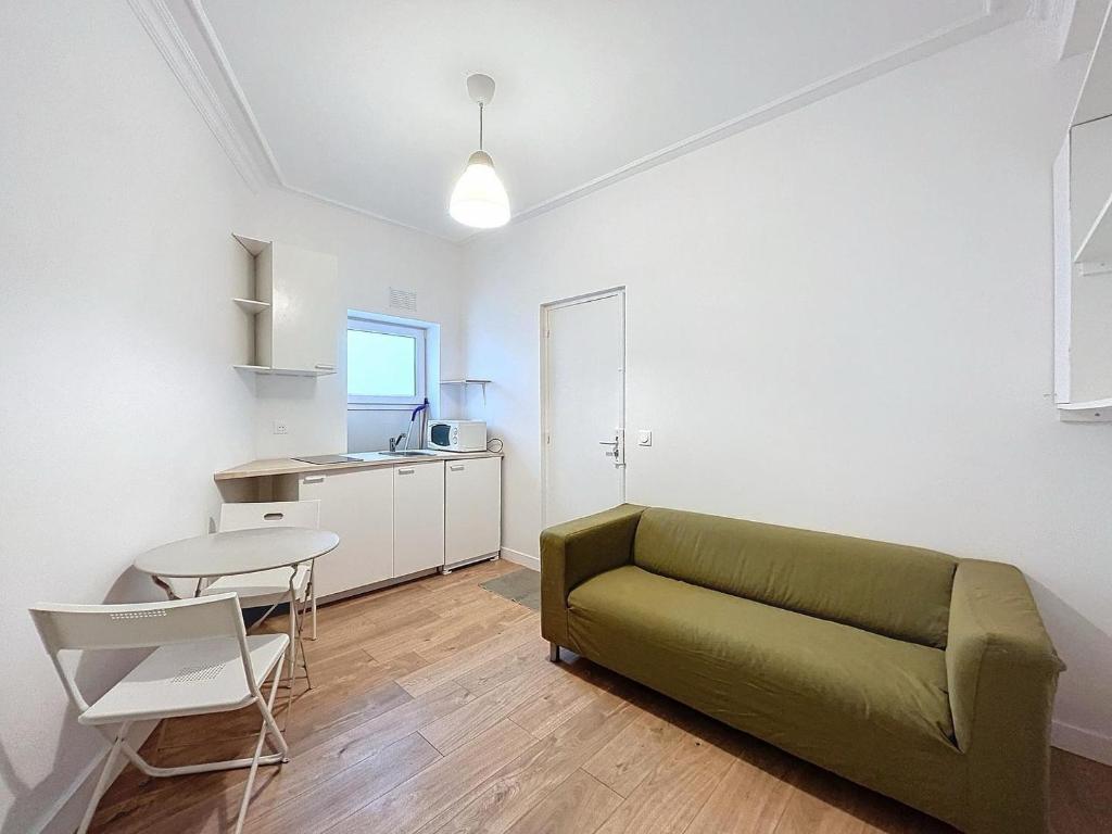 un salon avec un canapé vert et une table dans l'établissement L'Instinct - Centre-Ville - Métro Paris, à Levallois-Perret