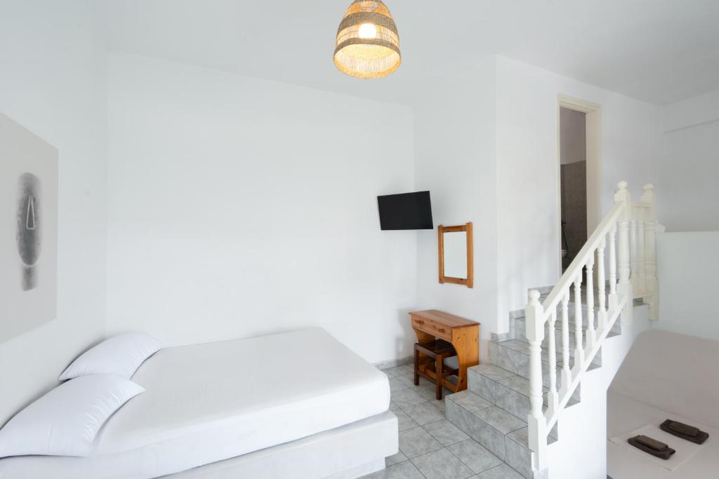 a white bedroom with a bed and a staircase at Perseas in Naousa