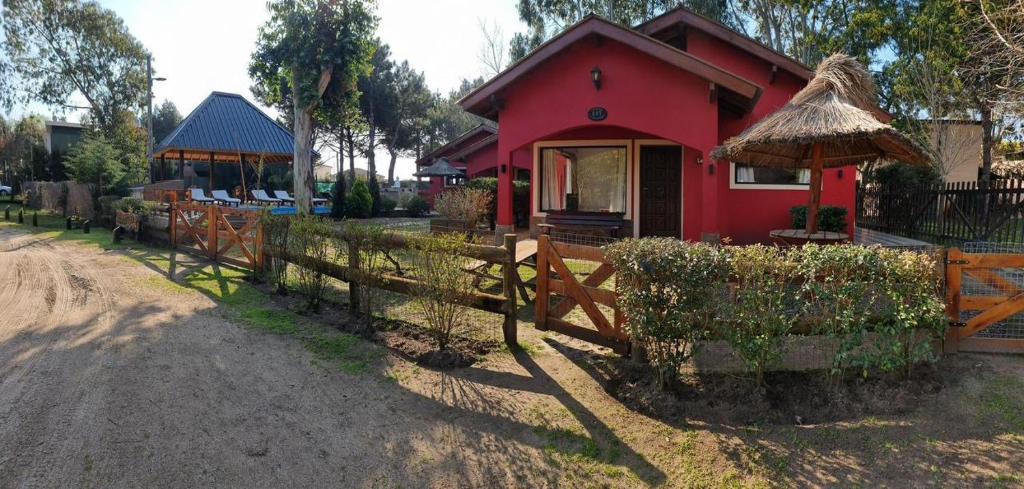 una casa roja con una valla delante en Cabaña La Yuli, en Santa Teresita