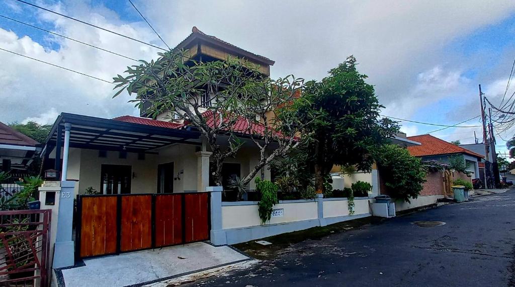 a white house with a red gate on a street at Casa Shanti in Nusa Dua