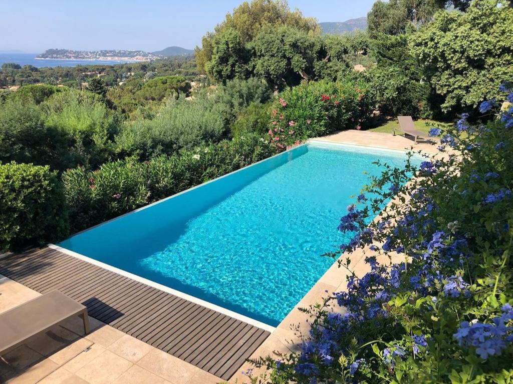 - une piscine dans un jardin fleuri dans l'établissement Très belle villa vue mer - Piscine à débordement, à La Croix-Valmer